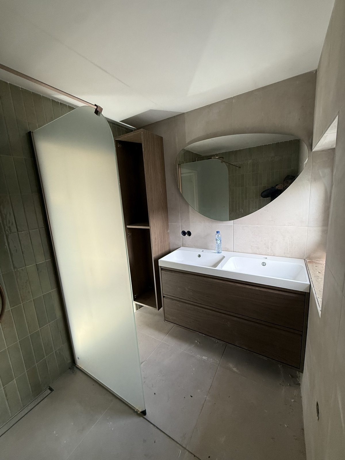 Badkamer met douchewand, wastafelmeubel en ovale spiegel