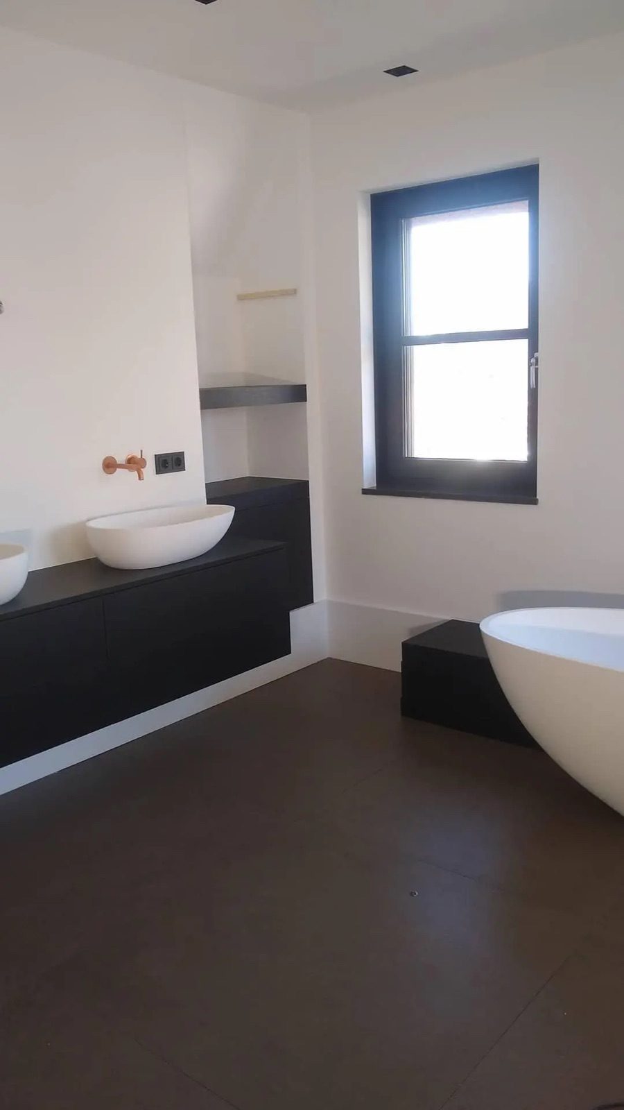 Badkamer met vrijstaand bad, wastafelmeubel en zwarte kozijnaccenten
