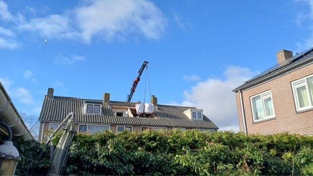 Kraan plaatst dakkapel aan de achterzijde van woningen