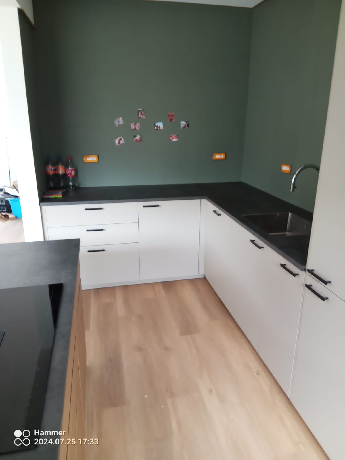 Keuken met groene wand, wit front en zwart werkblad