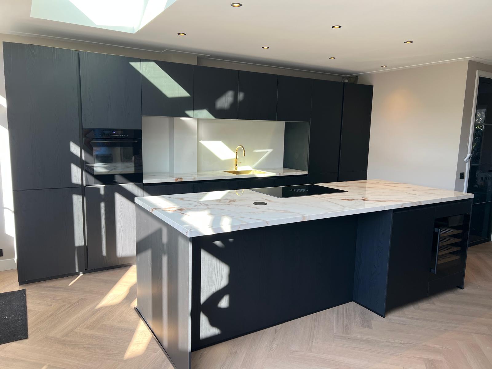Moderne zwarte keuken met marmer werkblad, lichtstraat en inbouwspots