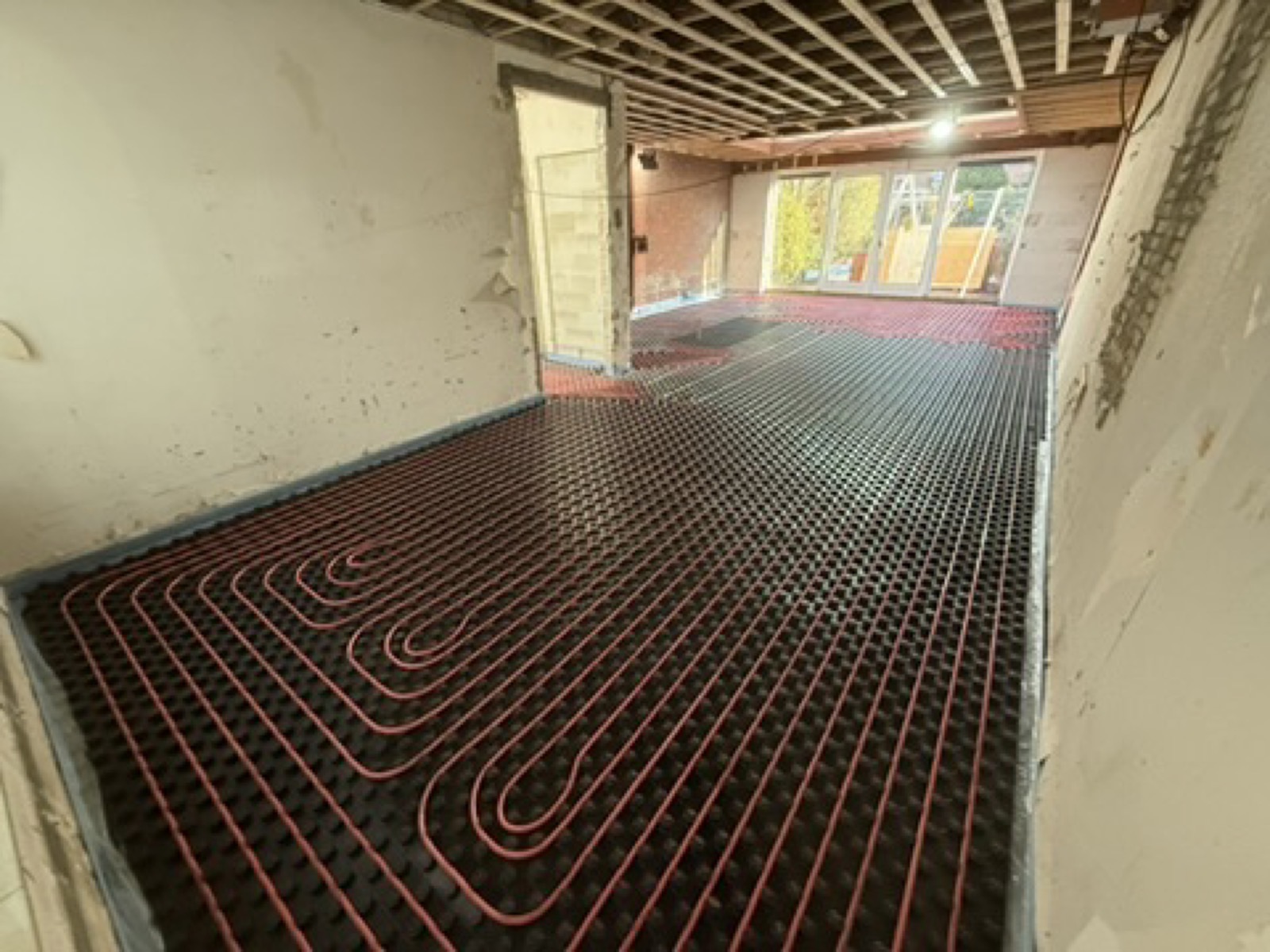 Vloerverwarming met rode buizen op noppenplaten door De Bouw Baron